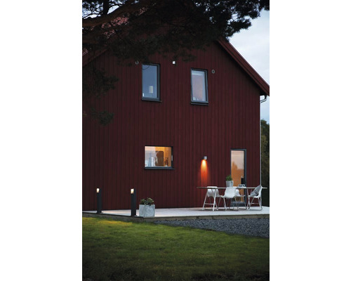 Husfasad med belysning, altan med bord och stolar i trädgården