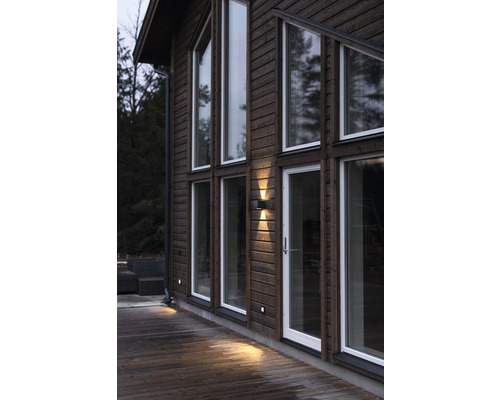 Trähusfasad med fönster, dörr och utomhusbelysning.