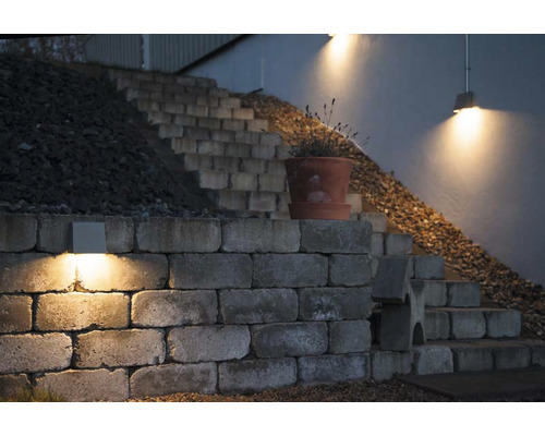 Belyst mur med trappa och blomlåda i trädgården.