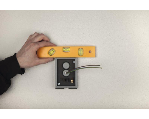 Hantverkare justerar ringklockans fäste med vattenpass