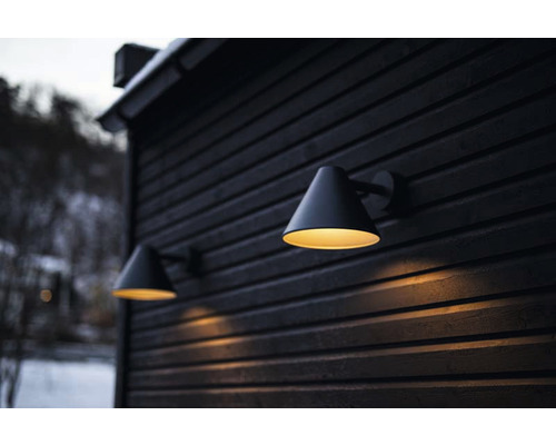 Två utomhuslampor monterade på en mörk träfasad