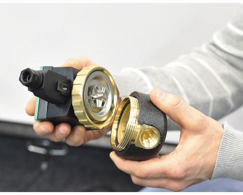 Skuren cirkulationspump med mässings- och plastkomponenter i handen.