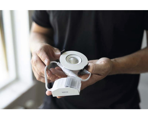 Man håller LED-spotlight med styrenhet i händerna