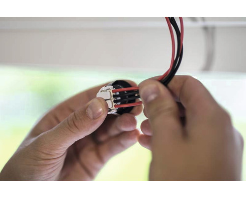 Närbild av händer som ansluter elektriska ledningar till en kopplingsplint