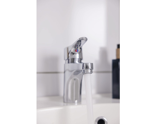 Kromad vattenkran med rinnande vatten i ett tvättställ.