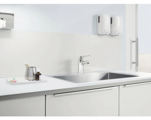 Ljus interiör med handfat, kran, tvålpumpar och förvaringsutrymme