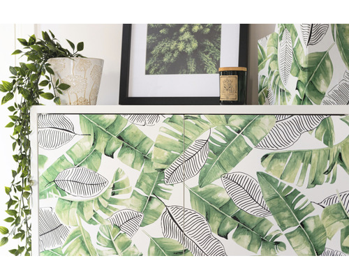 Skåp med bladmönster, krukväxt, inramad bild och ljus