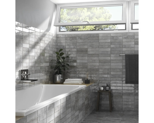 Badrum med badkar, tvättställsblandare, fönster och grå väggplattor