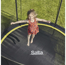En flicka hoppar på en Salta-trampolin i trädgården