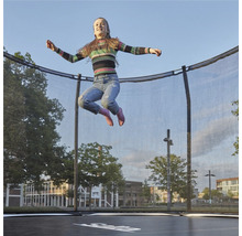 Flicka hoppar på en studtrampolin med säkerhetsnät