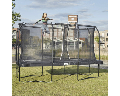 Rektangulär trädgårdstrampolin med säkerhetsnät och hoppande barn.