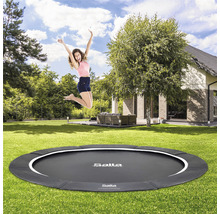En kvinna hoppar på en Salta-trampolin i trädgården.