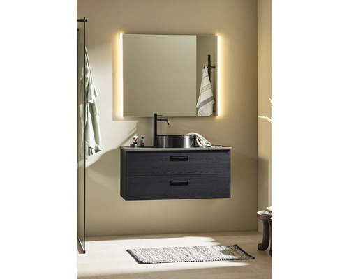 Badrum med underskåp för tvättställ, tvättställsskål, spegel med belysning och badrumsmatta