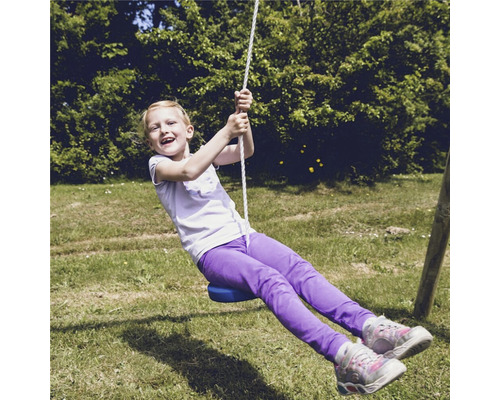 Flicka gungar på en linbana i trädgården