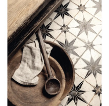 Detaljbild av golvplattor med stjärnmönster, kombinerat med träelement, en träsked och en trasa.