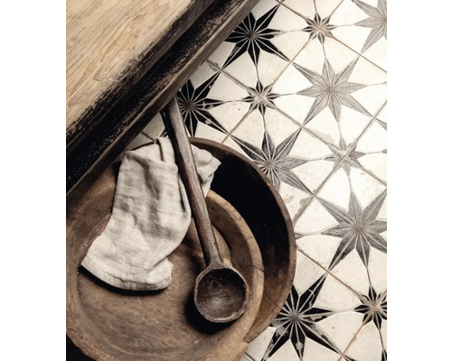 Detaljbild av golvplattor med stjärnmönster, kombinerat med träelement, en träsked och en trasa.