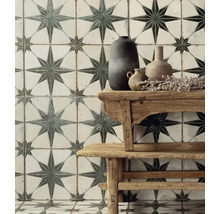 Vägg- och golvplattor med stjärnmönster bakom ett träbord med vaser