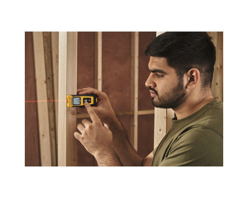 Man mäter på en trävägg med en digital laseravståndsmätare från Stanley