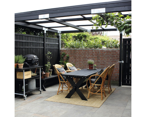 Övertäckt uteplats med matbord, rottingstolar, grillvagn och staket