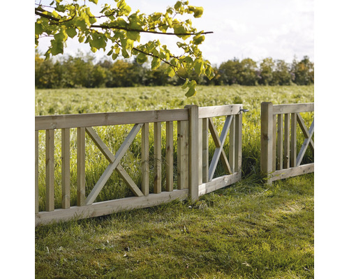 Öppet trästaket med X-formad design i ett grönt landskap