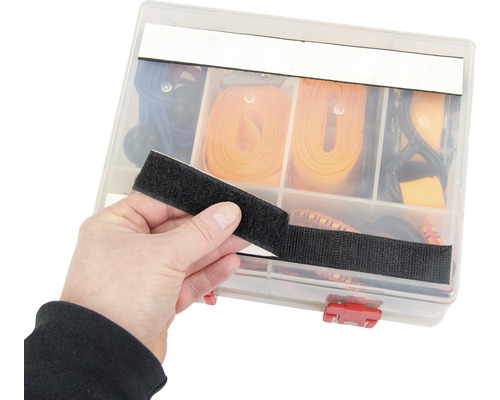 En person håller kardborreband framför en sorteringslåda med spännband.