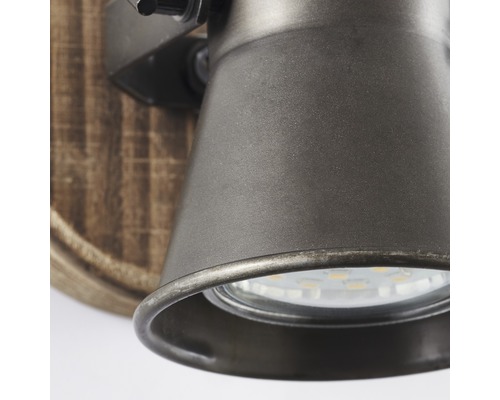 Detaljvy av en vägglampa med metallelement och träaccent