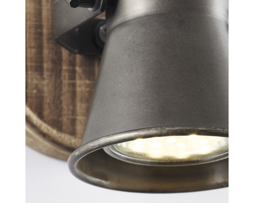 Närbild av en vägglampa med träfot och metallskärm