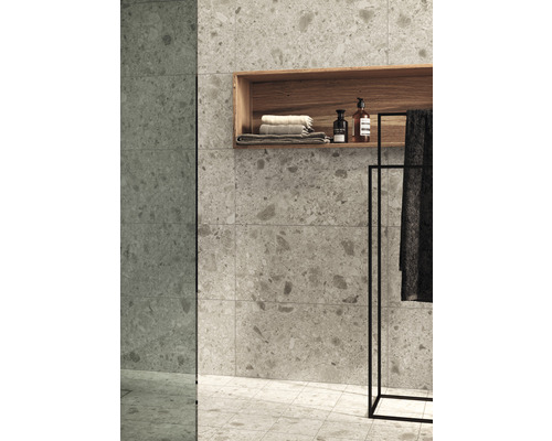 Badrum med kakelvägg, trähylla, handdukar och handdukshängare.