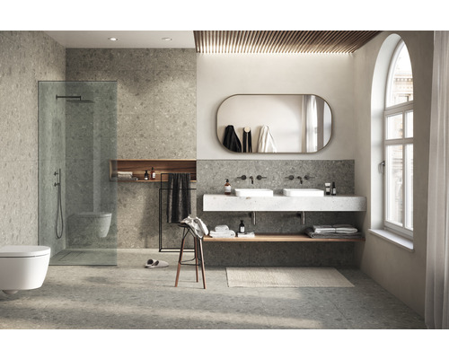 Ljust badrum med duschkabin i marknivå, dubbla handfat och stengodsplattor