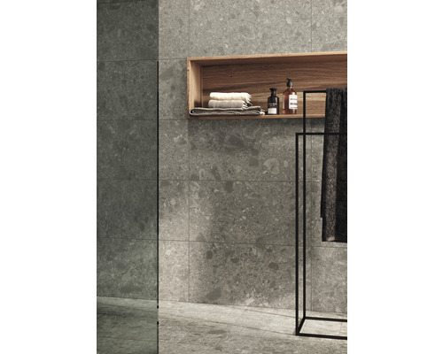 Badrum med grå plattor, trähylla, handdukar och badrumsartiklar.