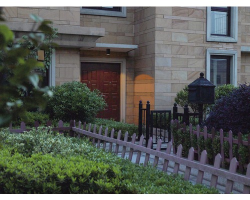 Husfasad med ytterdörr och dekorativt trädgårdsstaket.