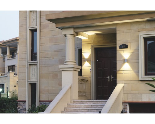 Entré till ett hus med stentrappor, pelare och utomhusbelysning