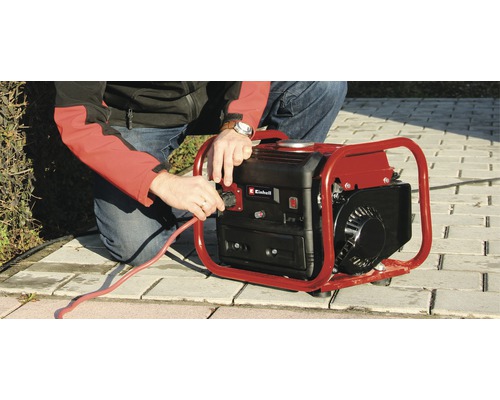 En man ansluter en röd strömkabel till en generator av märket Einhell.