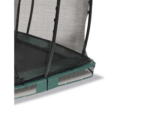 Detaljvy av en trädgårdstrampolin med säkerhetsnät och grön kantskydd
