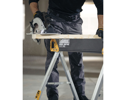 Hantverkare sågar trä på en Toughbuilt sågbock med en handhållen cirkelsåg.