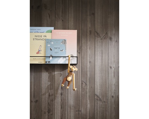 Barnböcker på en vägghylla med träfigur av en apa