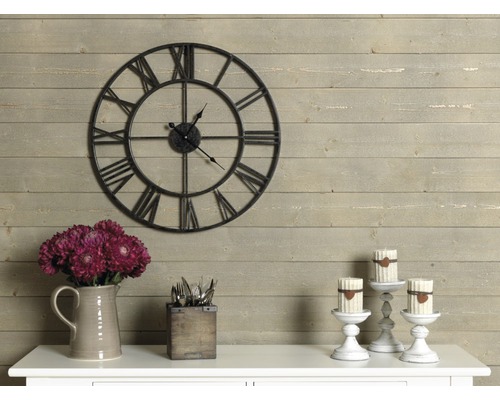 Dekorativ interiör med en väggklocka med romerska siffror, blommor, bestick och ljusstakar.