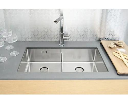 Dubbel diskho i rostfritt stål med kran i ett modernt kök