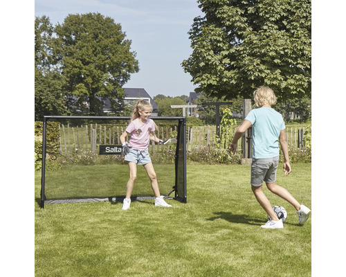Två barn leker med ett Salta fotbollsmål i trädgården.