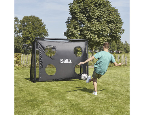 Pojke skjuter på ett fotbollsmål med målhål från Salta i trädgården