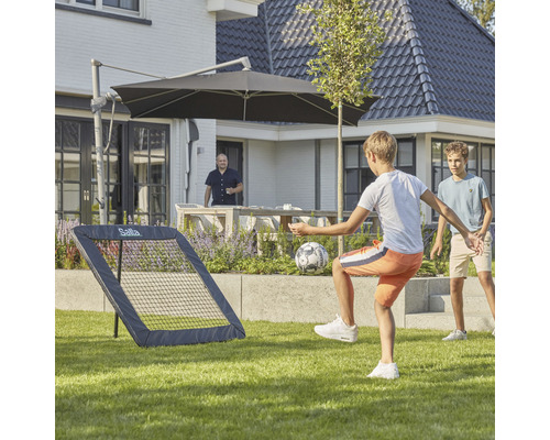 Pojkar leker med en Salta fotbollsretur i trädgården.