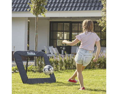 Flicka leker med Salta fotbollsmål i trädgården.