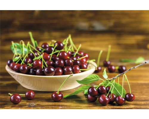 En skål med körsbär på ett träbord.