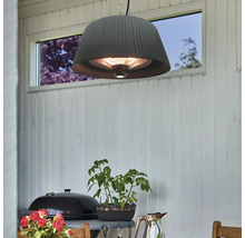 Mörk terrassvärmare med lampskärm hänger ovanför ett bord på en terrass.