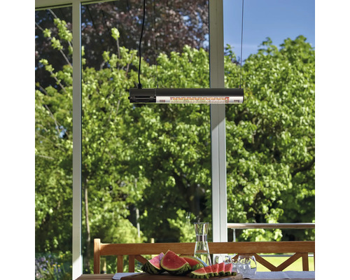 Utescen med hängande värmelampa över träbord med vattenmelon och drycker