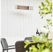 Terrass med infraröd värmare monterad på en vägg ovanför ett bord