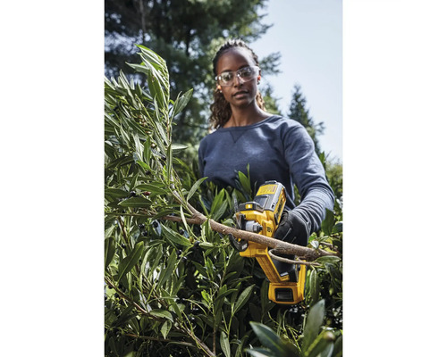 Kvinna klipper buske med DeWalt batteridrivna motorsåg