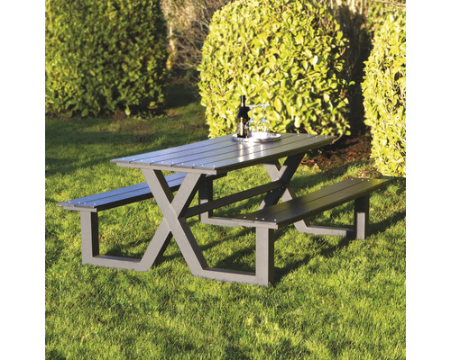 Grått picknickbord med bänkar i trädgården.