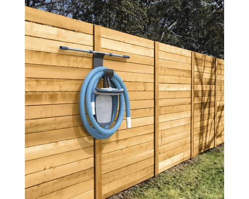 Poolrengöringsset med slang och hållare på ett trästaket