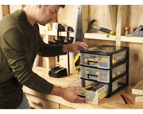 Man öppnar en låda i en verktygsförvaring i plast med tre lådor på en arbetsbänk.